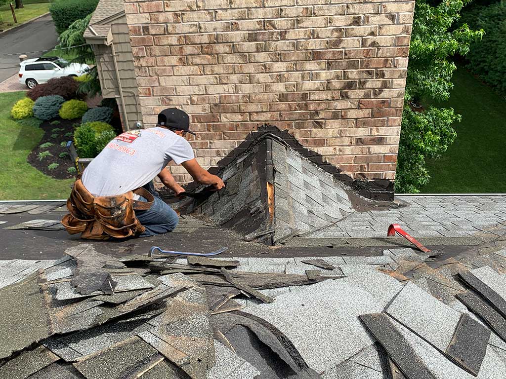 Brick chimney on a shingled roof under a cloudy sky
