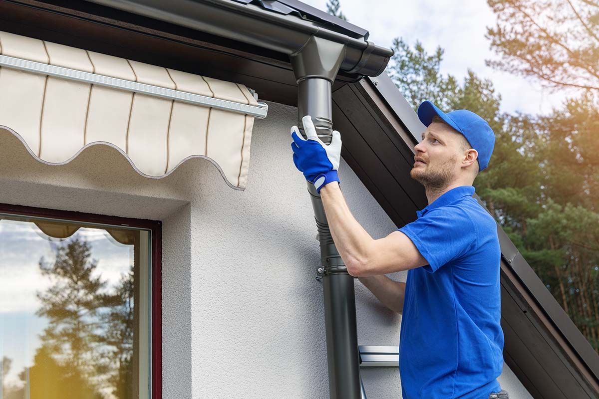 Technician cleaning or repairing a home gutter system